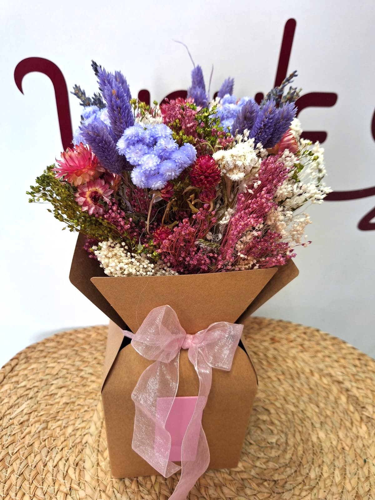 Ramillete de flor seca en tonos rosas y morados presentado en caja