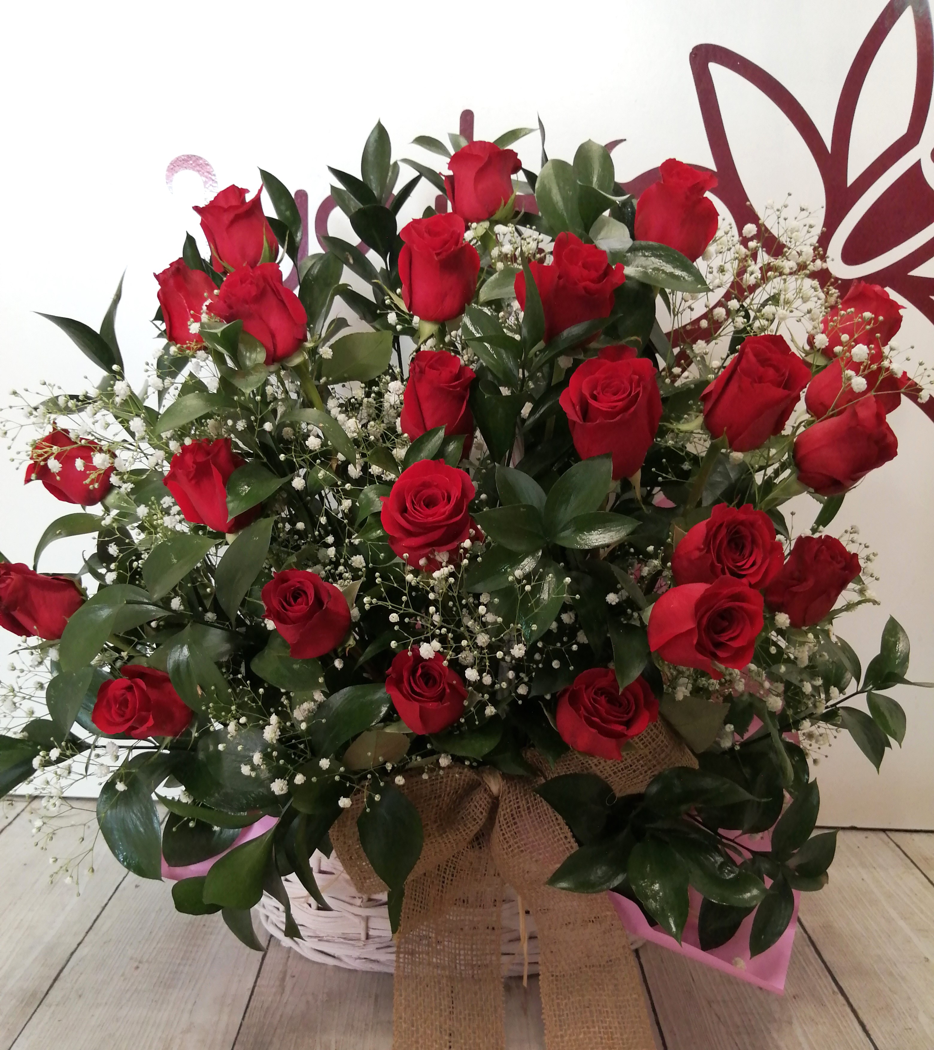 Canasto grande compuesto por 24 rosas rojas naturales con decoración